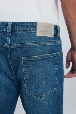 Calça jeans reta com lavagem escura e tingimento excessivo